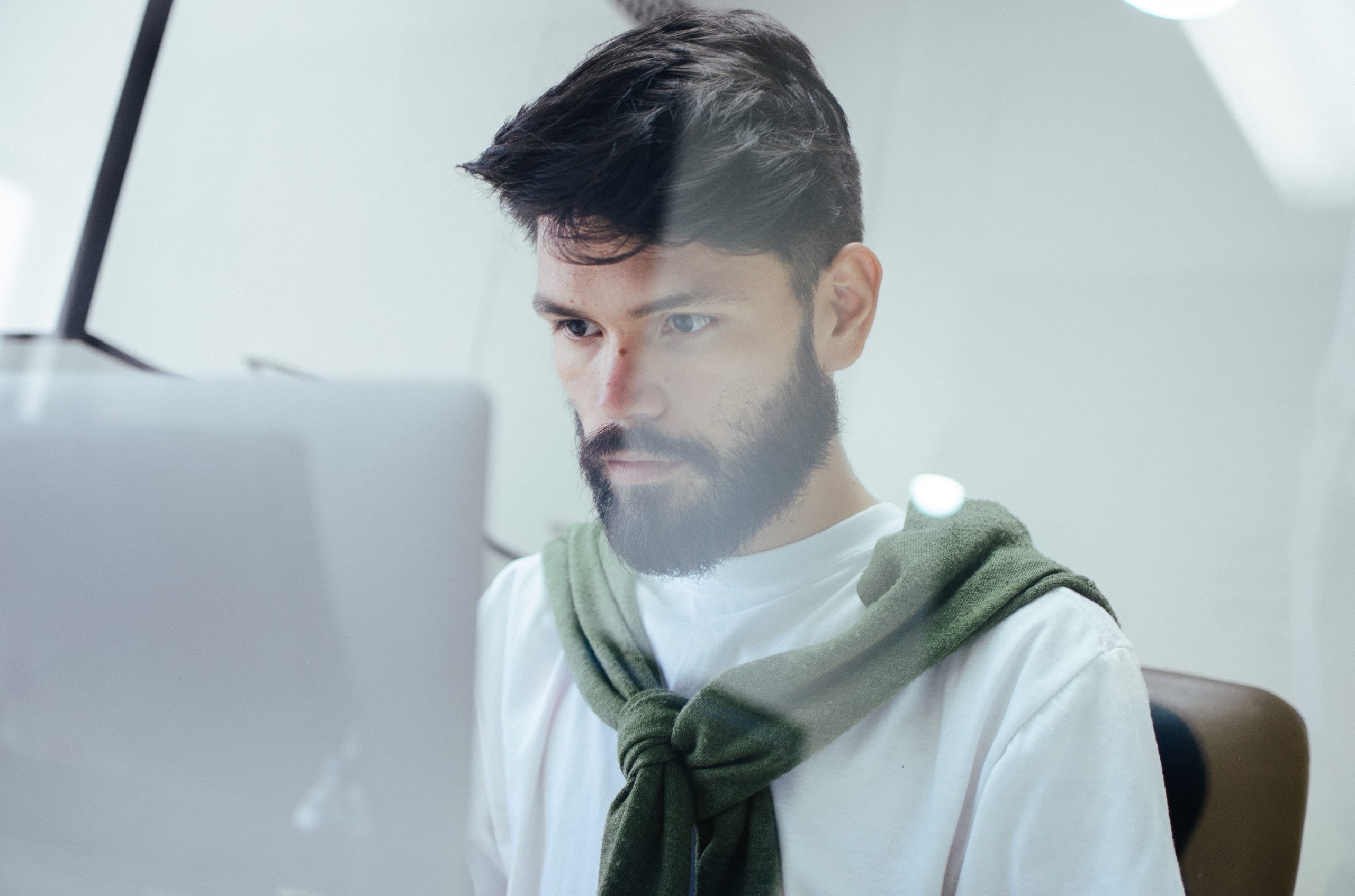 Hombre joven con barba sentado frente a un computador